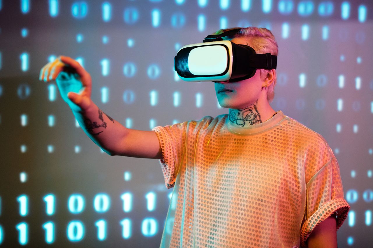 heros-img A person experiences virtual reality with a headset against a background of binary code.